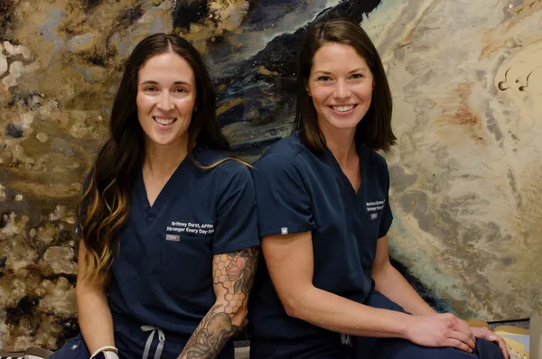 Two Stronger Every Day team members in navy scrubs at the practice
