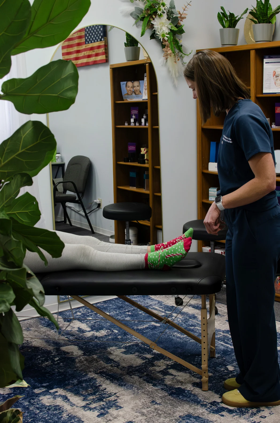 Clinician beside a person's lower legs on an exam table